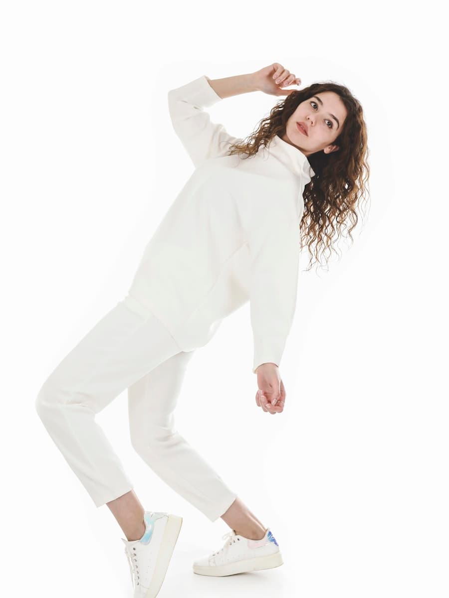 Model wearing a cream knitted turtleneck and matching tailored trousers