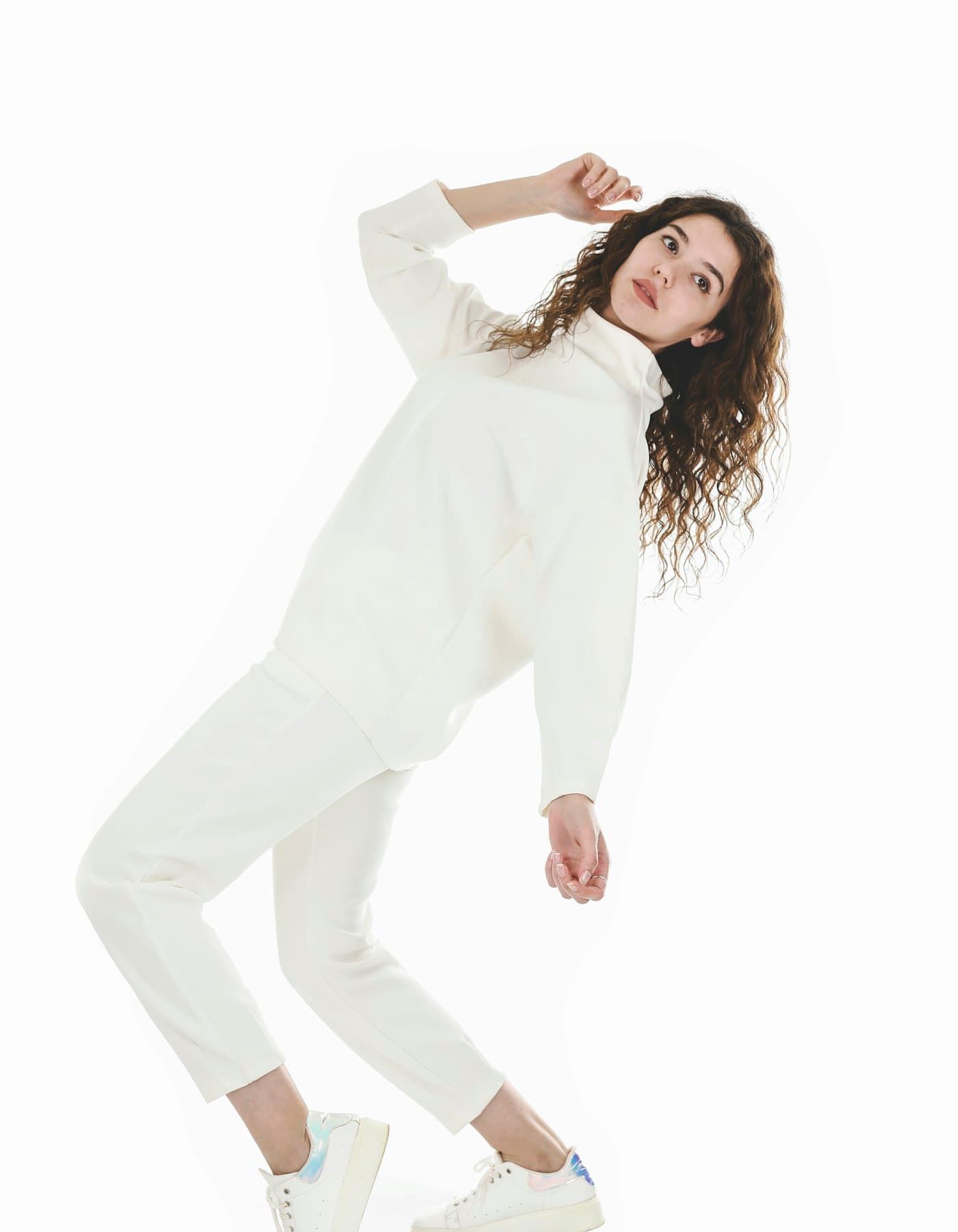 Model wearing a cream funnel-neck knit with matching tailored trousers