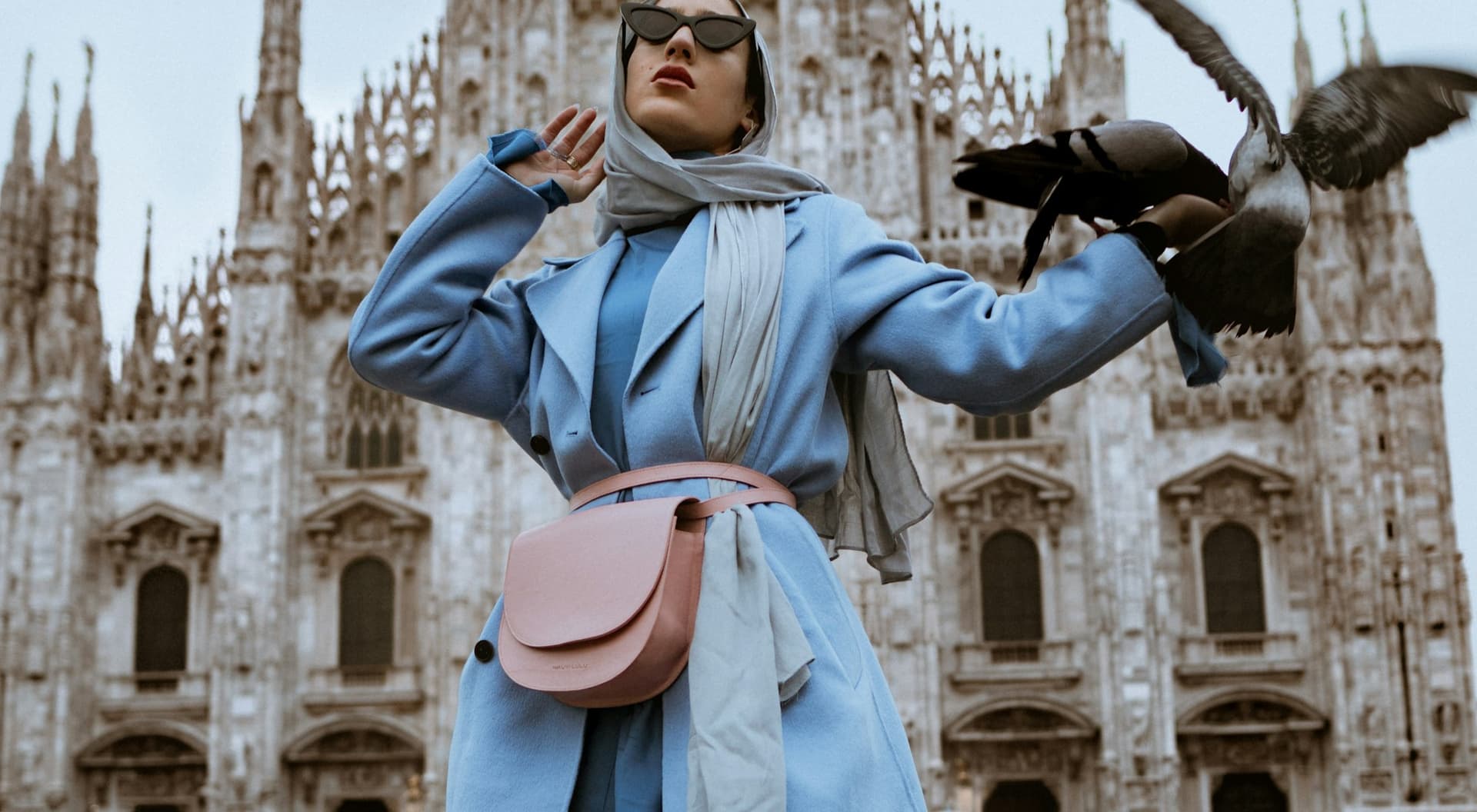 Model in a powder blue belted trench coat in a city square