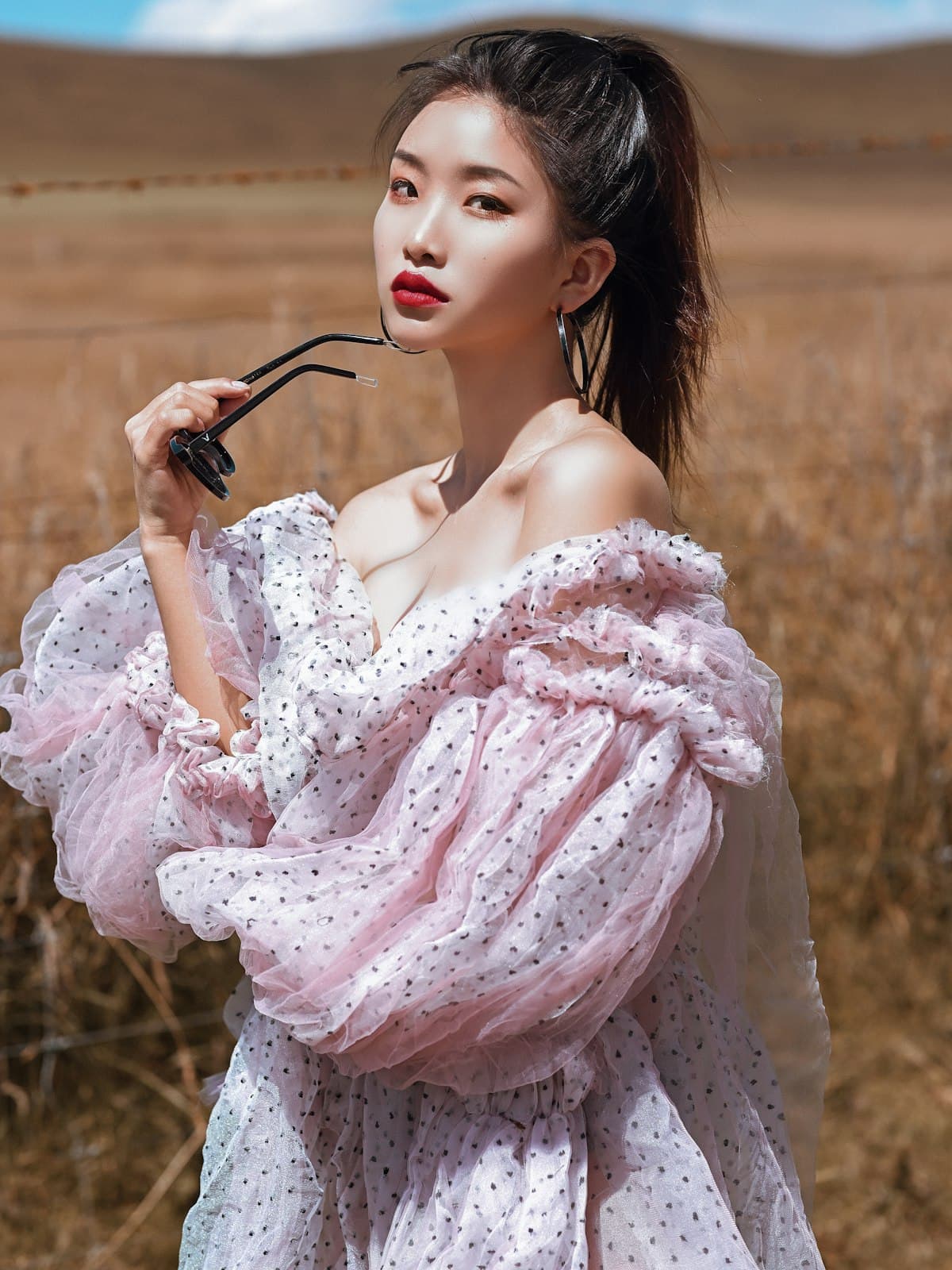 Model wearing the Blossom pink polka-dot organza dress in an open field
