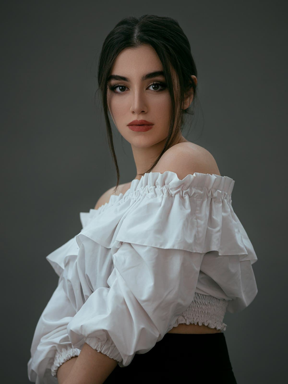 Model wearing the Celine white ruffled off-shoulder blouse in a dark studio