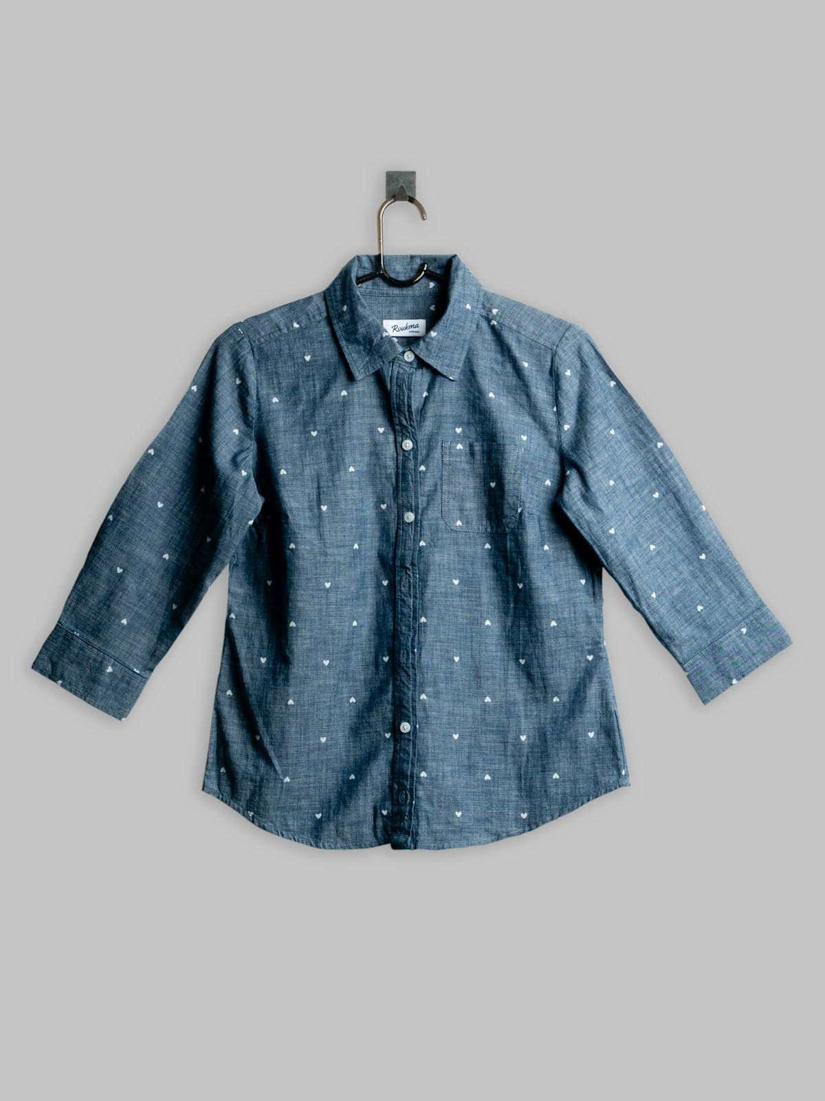 Blue chambray shirt with a woven dot pattern shown on a hanger