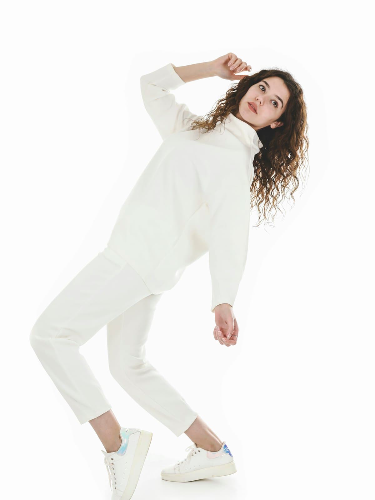 Model wearing the ivory funnel-neck knit and matching tapered trousers in a white studio