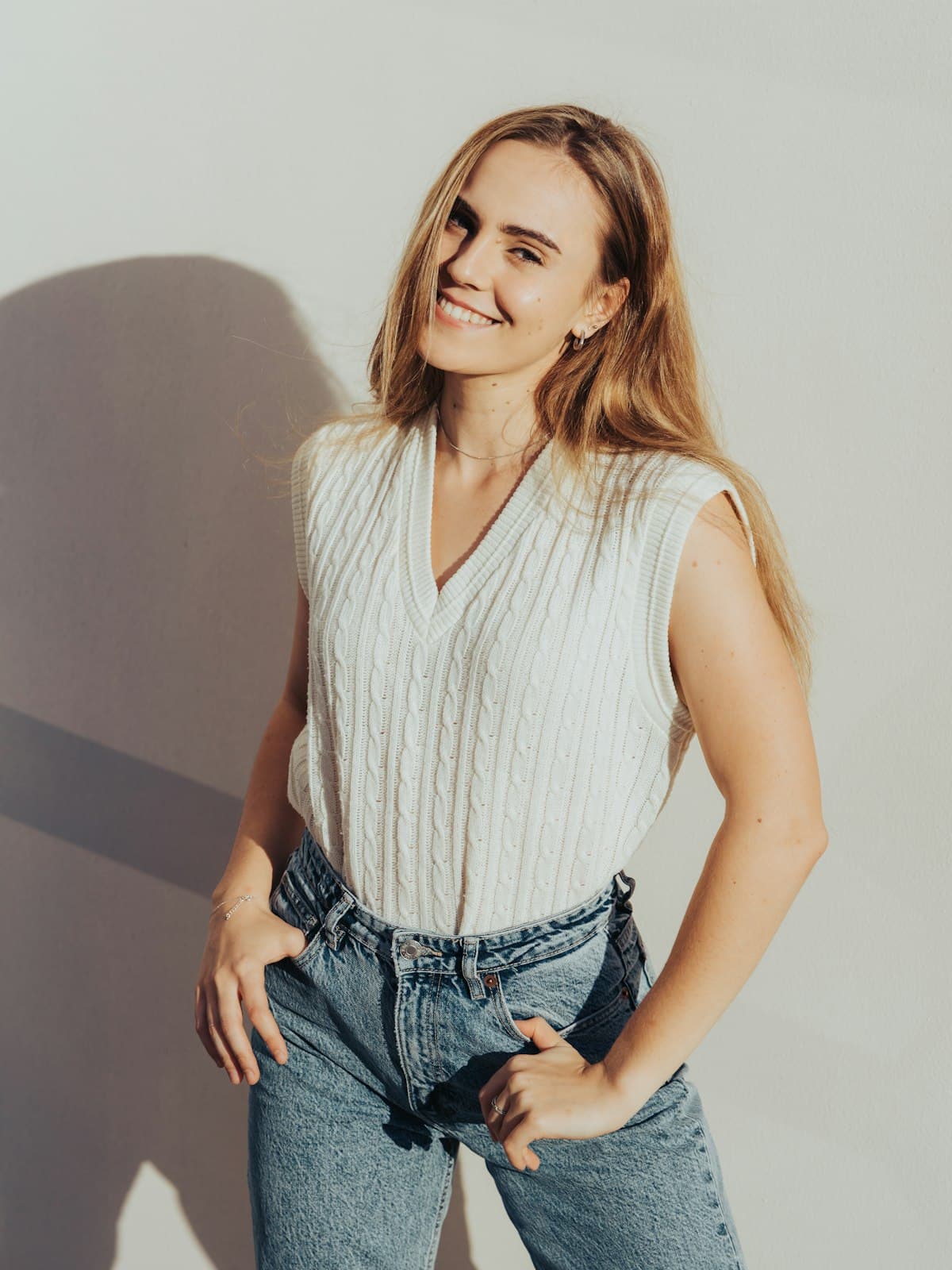 Model wearing the Luna cream cable-knit vest with light-wash jeans