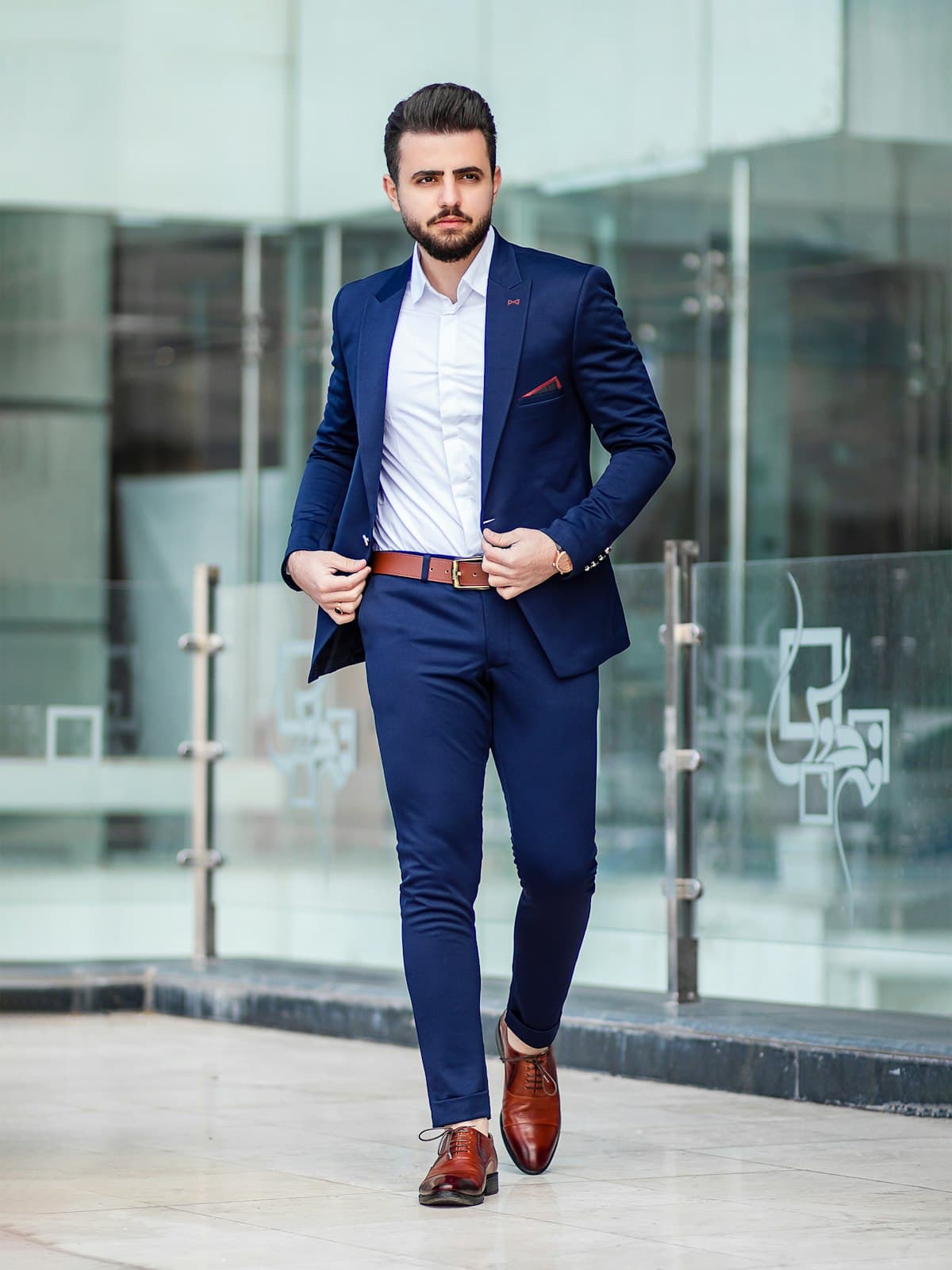 Model wearing a navy two-piece tailored suit with brown leather shoes