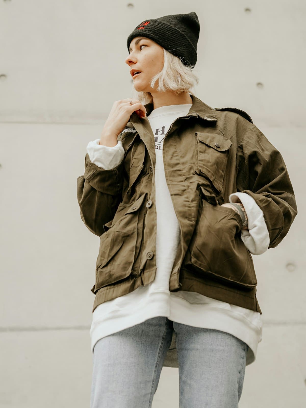 Model wearing the olive utility field jacket over a white sweatshirt