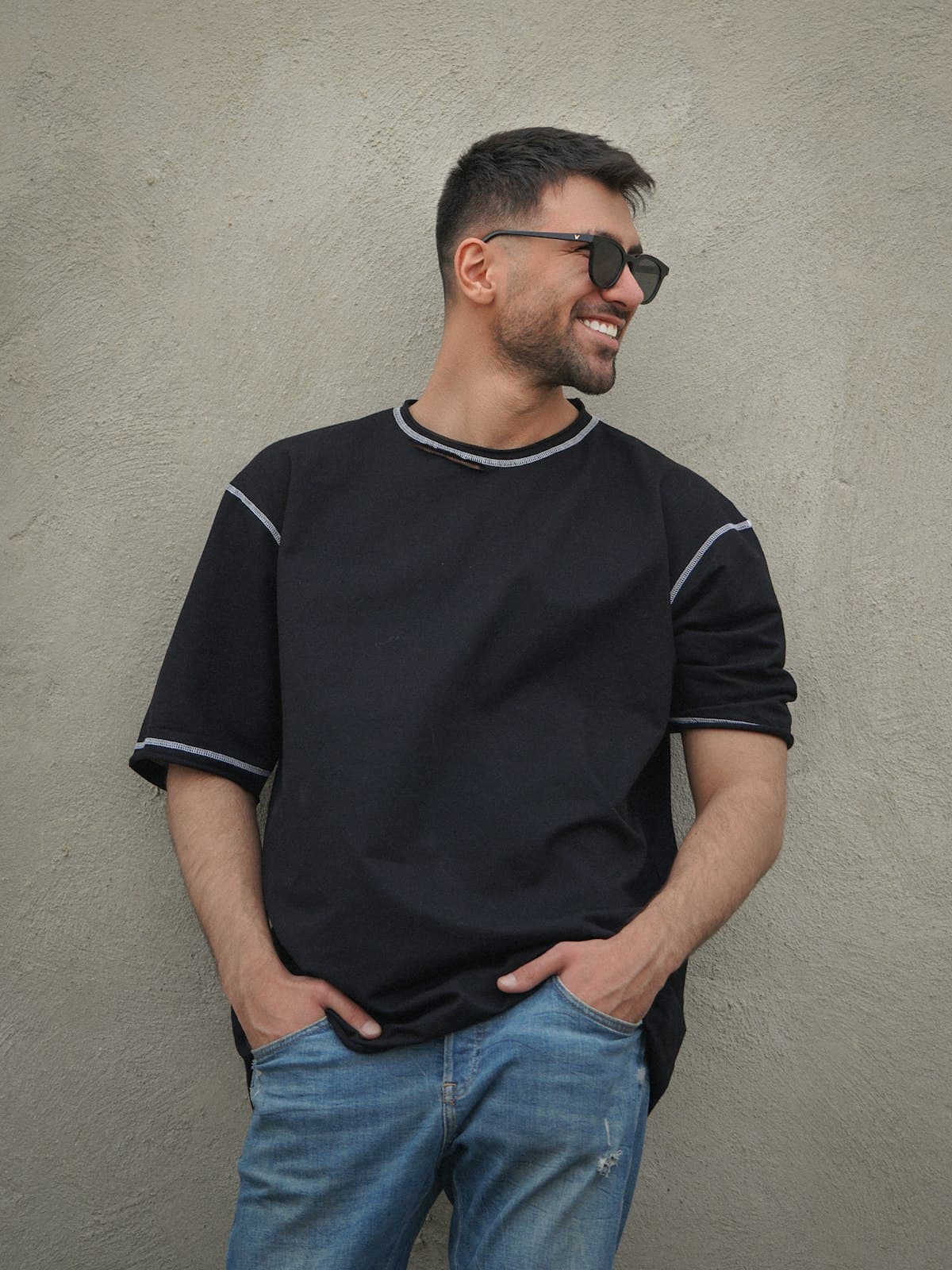 Model wearing a black oversized tee with contrast stitching and jeans