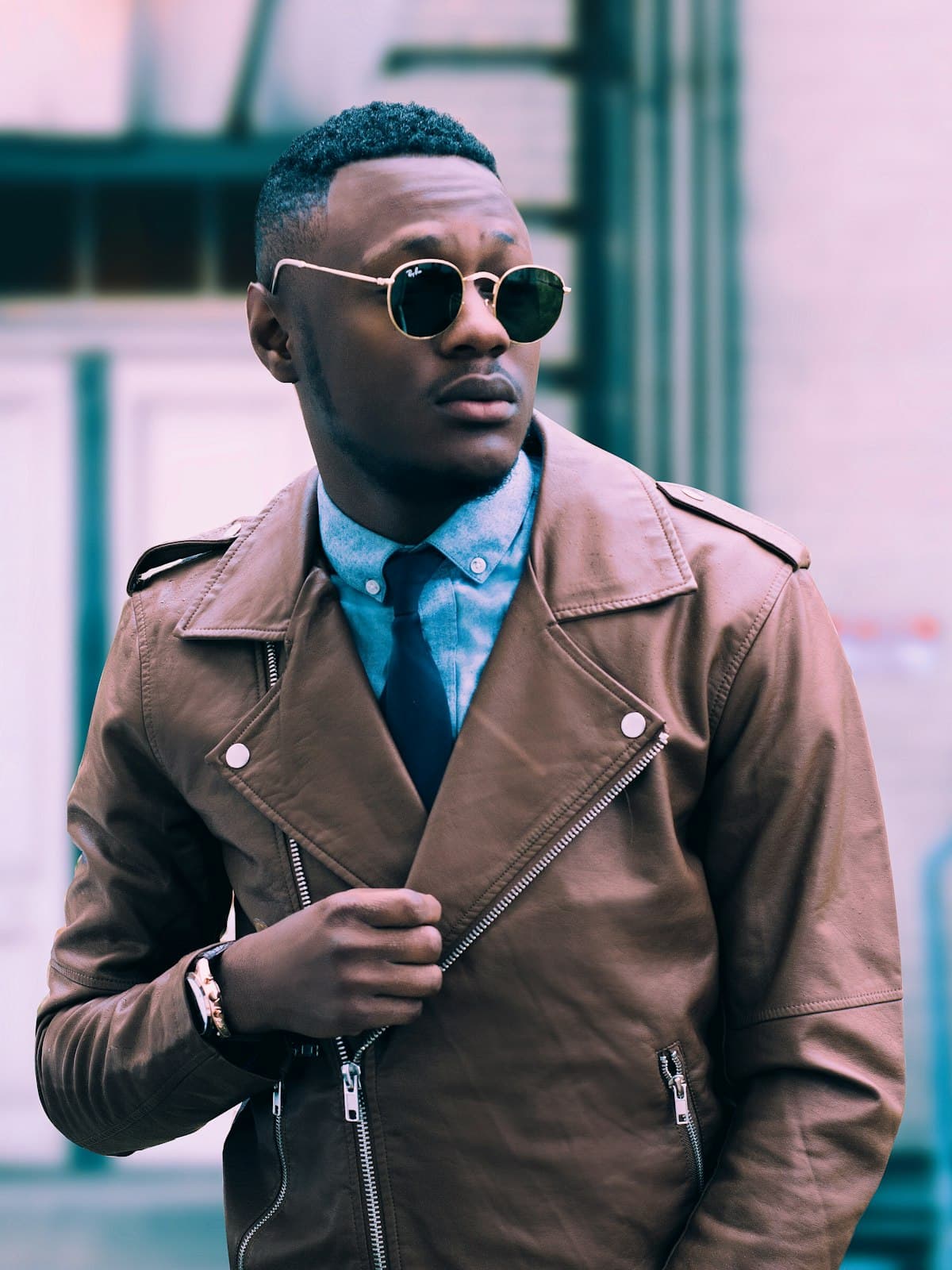 Model wearing a tan leather biker jacket over a shirt and tie