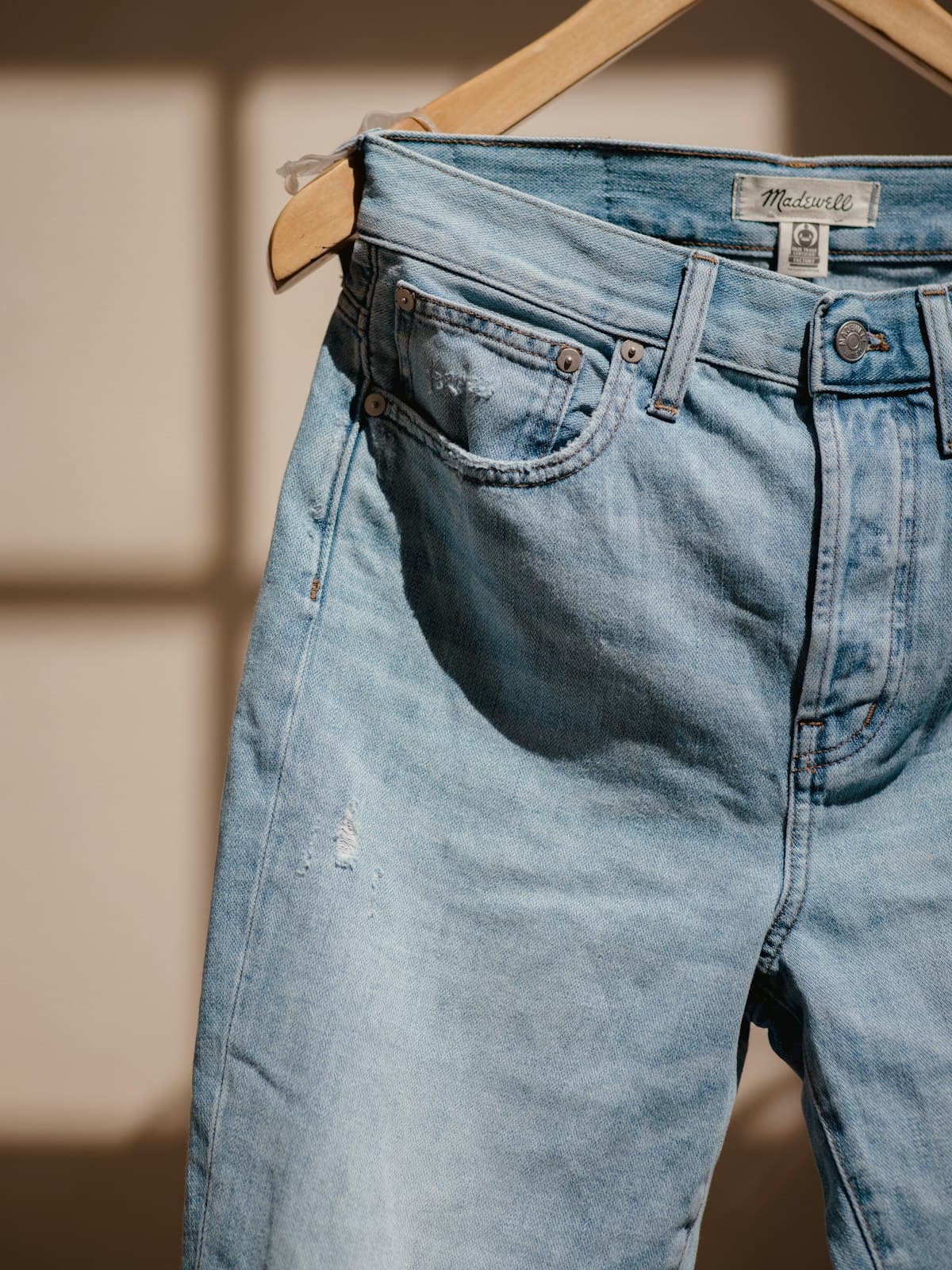 Light-wash high-rise jeans photographed on a wooden hanger