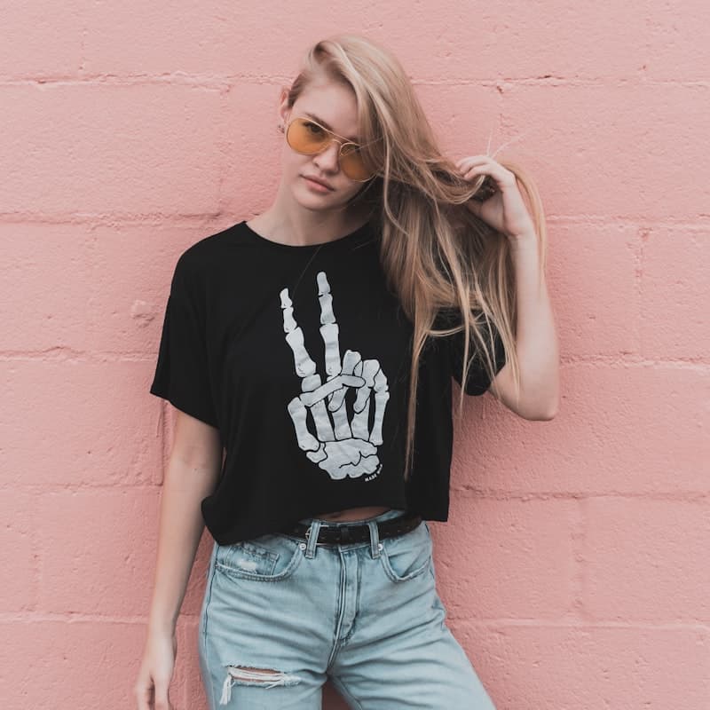 Model in a black graphic crop tee against a pink wall