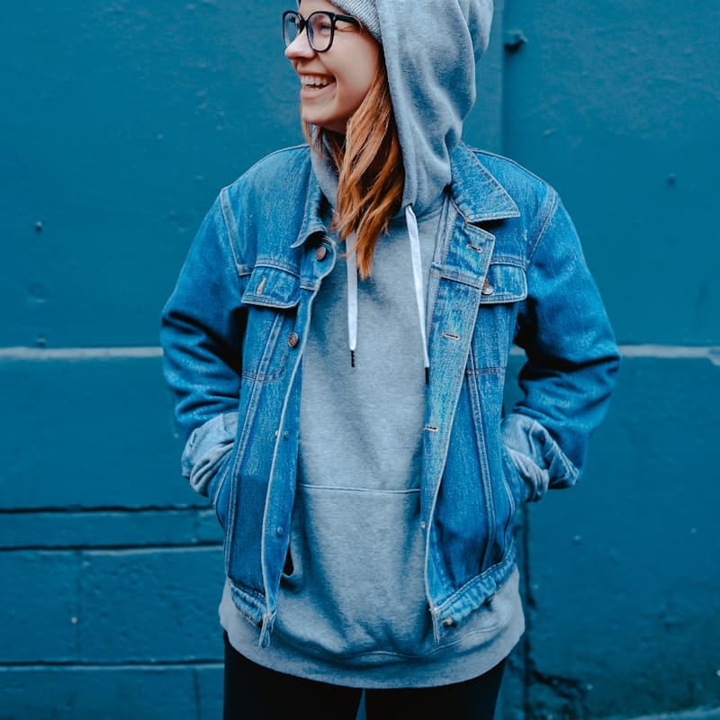 Model in a denim jacket layered over a grey hoodie